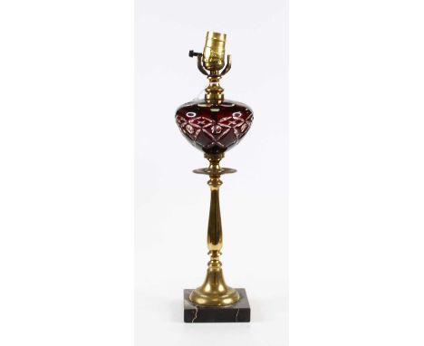A Victorian brass oil lamp, later converted for electricity, having a cranberry overlaid glass font, height 44cm