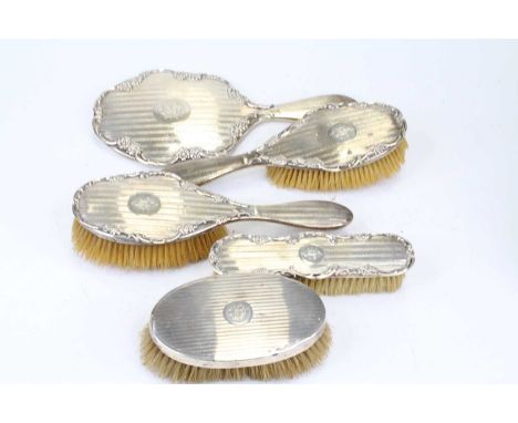 An early 20th century silver backed five-piece dressing table set, comprising hand mirror, hairbrushes and clothes brushes, e