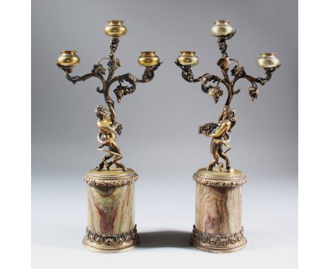 A SUPERB PAIR OF SILVER GILT THREE LIGHT CANDLESTICKS, with satyr holding three scrolling branches, with fruiting vines, supp