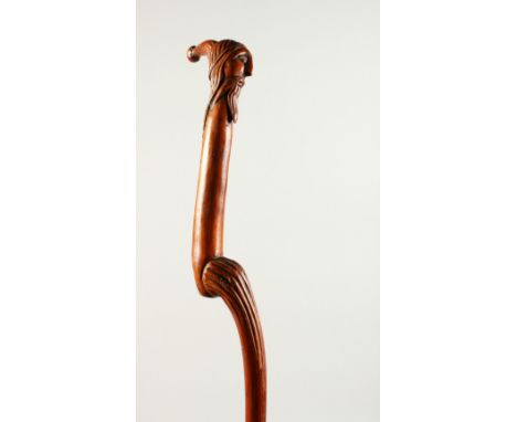 A SLENDER CARVED WOOD WALKING STICK PIXIE. 92cms long.