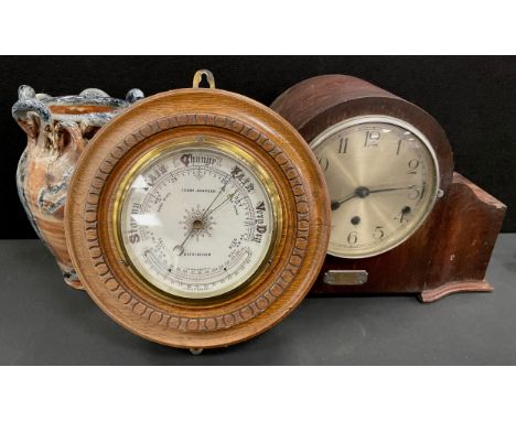 A late 19th / early 20th century aneroid barometer, oak mount carved to front, inset with the barometer, white enamel dial, i
