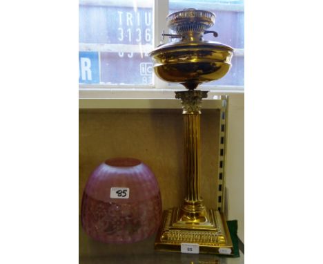 A Corinthian column  brass oil lamp with pink glass shade, 67cm high overall 