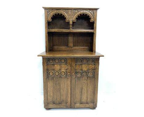  20th century carved oak dresser with one height plate rack over panelled cupboard enclosing shelf and two drawers, raised on