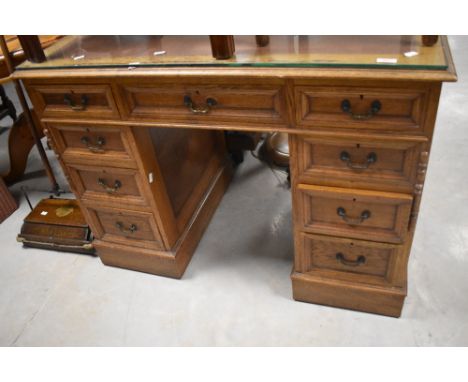 An early 20th century light oak pedestal desk, with inset tooled brown leather skiver and arrangement of nine drawers 77cm x 