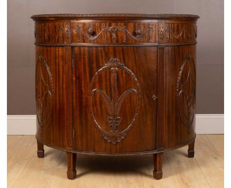 An Adam style demi-lune mahogany commode by Maple &amp; Co., the frieze with swag decoration to the cupboard doors and with f