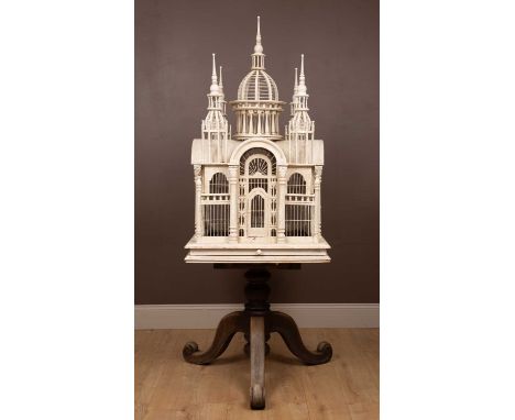 A white painted birdcage with domed crossing roofs, a central dome and further spires to either corner, with decorative colum