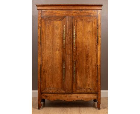 A 20th-century French elm armoire with brass mounts and escutcheon, the shaped apron in between cabriole legs, the cupboard d