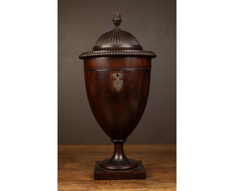 A 19th century mahogany cutlery urn of classical form with a reeded lid beneath a pinecone finial, the lid rising to reveal r