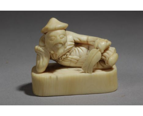 An 18th century Japanese netsuke from Edo period. Not signed. In carved elephant ivory depicting a Mandarin character lying o