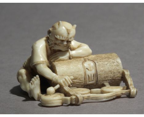 A Japanese netsuke circa 1870-1880. Not signed. In carved ivory portraying an Oni sat on the floor resting over a big rolling