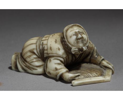 A 19th century Japanese netsuke from Edo period. Not signed. In carved ivory portraying a woman lying on the floor and holdin