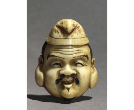 A late 19th century Japanese netsuke from Meiji period. Signed on the back. In carved elephant ivory portraying a mask of Ebi