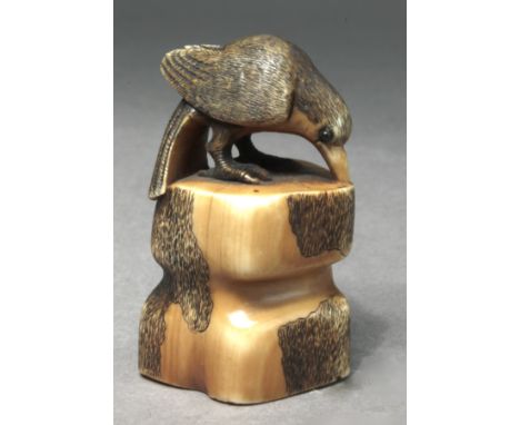 A 19th century Japanese netsuke. Not signed. In carved elephant ivory portraying a raven with horn eyes over a trunk, 4x2x2,5