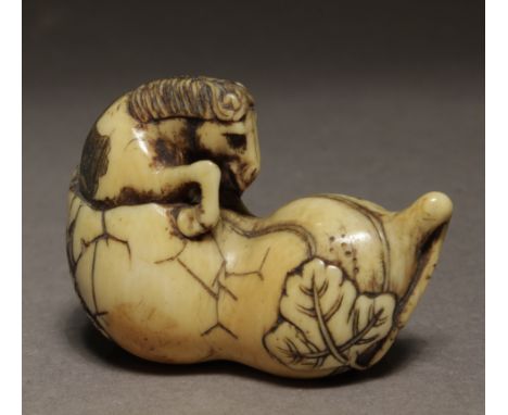 An early 19th century Japanese netsuke from Edo period. Not signed. In carved icory portraying a horse trying to get out from