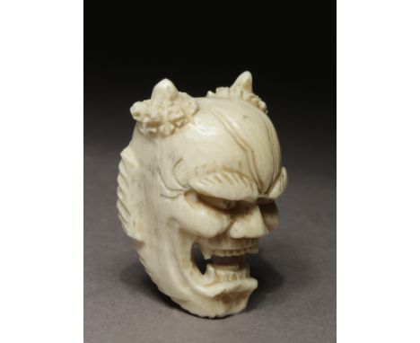A Japanese netsuke from Meiji period circa 1900. In carved elephant ivory portraying a mask of the female demon 'Hannya' wear
