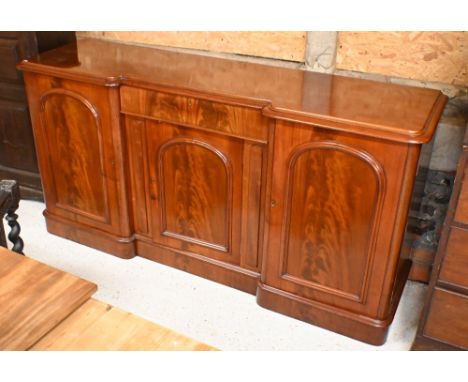A Victorian figured mahogany inverted breakfront sideboard with central drawer and arch panelled cupboards on plinth base, 18