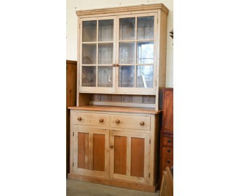 A vintage pine dresser with glazed doors enclosing two shelves, on a cabinet base with two drawers over panelled cupboards, 1