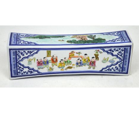 A Chinese porcelain headrest with hand painted decoration of costumed children playing boardgames with landscape scenes, widt