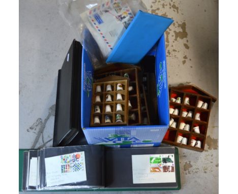 A collection of ceramic thimbles with nine sectional holders and a folder of first day covers, an album of stamps and some lo