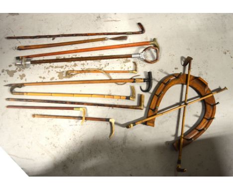 An oversized oak horseshoe mounted with crossed riding crops, a quantity of crops, walking sticks and a shooting stick.   CON
