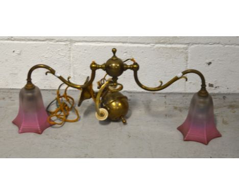 An Edwardian brass two-branch adjustable light fitting with graduating pink bell shaped shades, width 65cm.