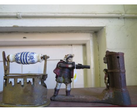A Victorian style cast iron money box in the form of a William Tell type figure shooting an apple off a boy before a castle, 