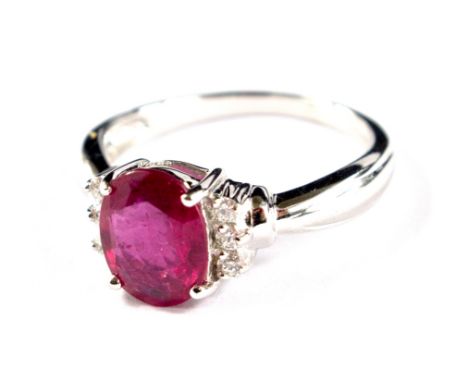 An 18 carat white gold ring set with an oval ruby with three diamonds to each side