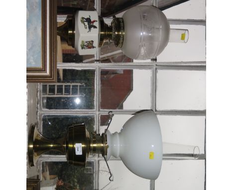 Two brass oil lamps, one with ceramic reservoir depicting huntsmen