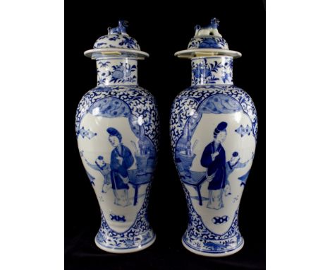 A pair of Chinese blue and white baluster vases and covers, the domed covers with dogs, over panels depicting a lady and a bo