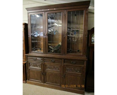 LATE 19TH CENTURY OAK BOOKCASE WITH THREE LEADED AND GLAZED DOORS, THE BASE FITTED WITH THREE DRAWERS OVER THREE CARVED PANEL
