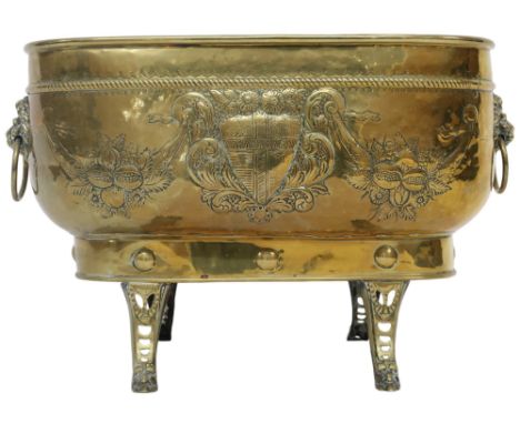 A VICTORIAN BRASS OBLONG PLANTER&nbsp; embossed with armorial shield and floral motifs with lion masque ring handles on out s