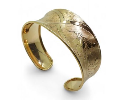 AN 18K GOLD BANGLE the Italian made wide bangle has hand engraved floral detail throughout. Dimensions at widest point 2.5cm.