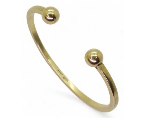 A 9CT GOLD BANGLE the classic ball terminal bangle, is solid gold made by Thropp &amp; Co London 1975. Inner diameter 6cm x 4