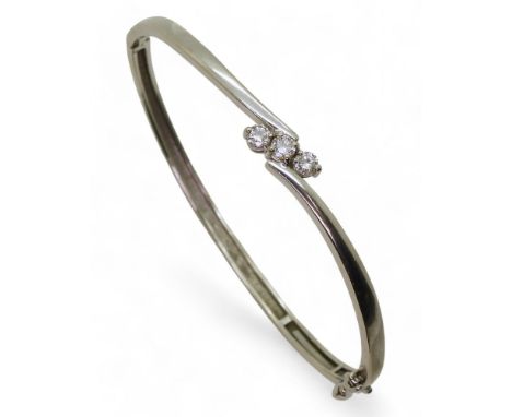 A DIAMOND BANGLE mounted in 9ct white gold and set with three brilliant cut diamonds, with a combined diamond carat weight of