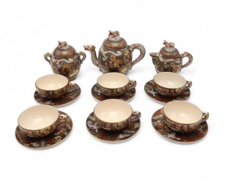 A SATSUMA TEA SERVICE  Painted and moulded with dragons and Gods, comprising; teapot, sugar bowl, cream jug, six cups and six