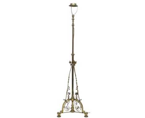 AN ARTS AND CRAFTS BRASS&nbsp; TELESCOPIC STANDARD LAMP&nbsp; with tripod base decorated with scrolls and twists on cup feet,