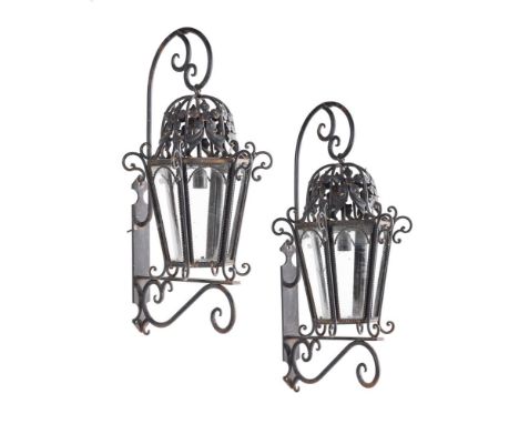 A PAIR OF BLACK PAINTED WROUGHT IRON EXTERIOR WALL LANTERNS20TH CENTURYEach with wall bracket and scroll work, the lanterns e