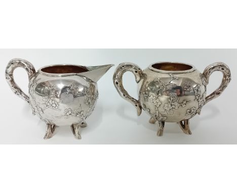 A Chinese silver cream Jug and Sugar Basin of globular form with ‘root’ handles and prunus in relief on four peg feet. 13.20o