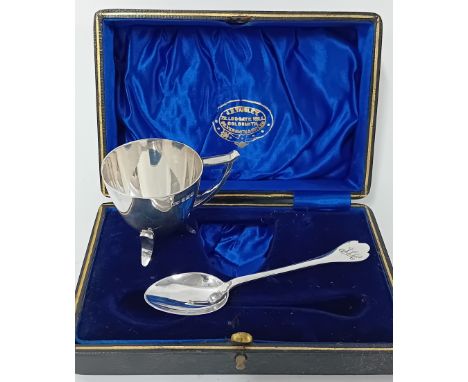 A silver egg cup on feet and a spoon, hallmarked Sheffield 1915, cased, together with a silver baby spoon and pusher, cased, 