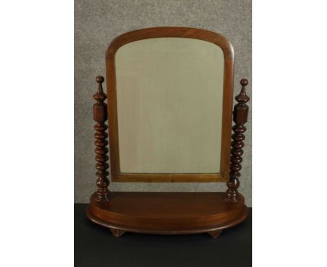A Victorian walnut dressing table or toilet mirror, of rounded arch form supported by bobbin turned columns, on a bow fronted