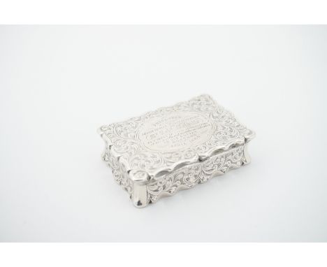 A Victorian silver snuff box, of shaped rectangular section, with engraved scrolling foliage to the case back, sides and face