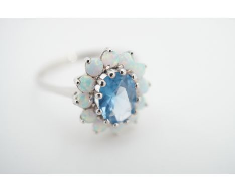 A contemporary 9ct white gold, blue tourmaline and opal flower head cluster dress ring, with central oval-cut tourmaline of a