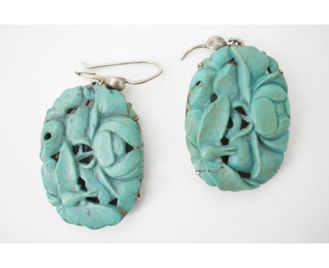 A vintage pair of carved turquoise ear pendants, depicting insects and blossom, claw-set on white-metal (test as silver), wit