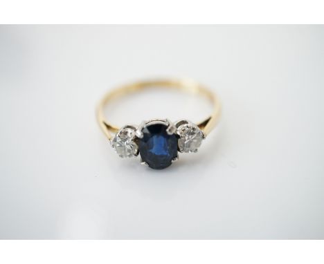 A vintage three-stone diamond and sapphire dress ring, having a central oval-cut sapphire of approximately 1ct, flanked by a 