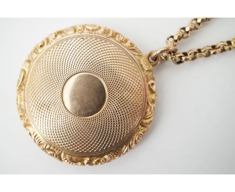 An antique yellow-metal locket, with engine-turned back and foliate engraved border, stamped '9ct' (tests as gold), locket ap