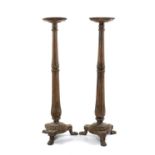PAIR OF CARVED OAK TORCHÈRES, fluted baluster columns to tripod bases, on lion's paw feet, 135cms (