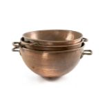 THREE GRADUATED COPPER COOKING BOWLS, rounded bottoms, with riveted copper handles, largest 56cms (