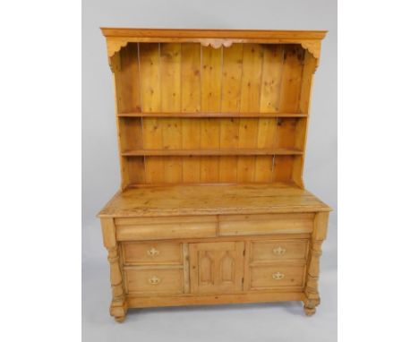 A Victorian pine dresser, the two shelf Delft rack over a cushion drawer, above a central cupboard door flanked by two pairs 