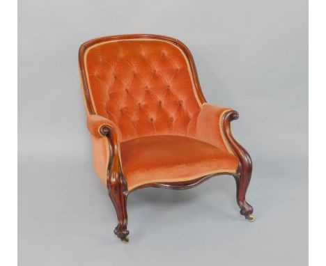A Victorian mahogany spoon back nursing chair, upholstered in red button back draylon, raised on cabriole legs, on castors.