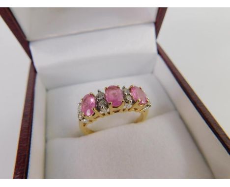A three stone pink sapphire ring interspersed by pairs of diamonds at intervals, set in yellow metal, marked 14ct, size M, 3.
